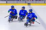 Three Para ice hockey players on ice talking to each other