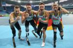 Four German men celebrate with clenched fists with a stadium behind them.