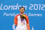 A picture of a man standing with his gold medal around his neck during a medal ceremony