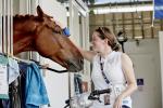 a para equestrian rider pats her horse in the stables