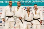four male judoka stand on a podium