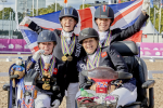 a group of Para riders celebrate their gold medal with a British flag behind them