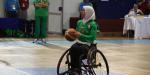 Woman wearing a hijab shooting a basketball in a wheelchair