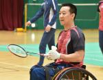 A male Para badminton player holds a shuttlecock and racquet