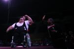 a male powerlifting raises his fist in celebration as he's wheeled off stage