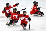 four male Para ice hockey players celebrate on the ice