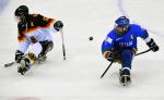 two male Para ice hockey players contest a puck