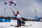 a male Para Nordic skier celebrates with the South Korean flag