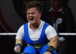 a female powerlifter clenches her fists on the bench