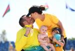 Men in a wheelchair holding a baby and kissing his wife 