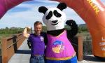 Short-statured man and a mascot dressed like a panda bear pose for a picture