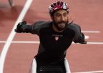 a male wheelchair racer throws his arms up in celebration