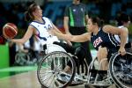 Woman in wheelchair holding a basketball while another tries to defend her