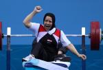 female powerlifter Fatma Omar punches the air while sitting on the bench