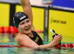 female Para swimmer Liesette Bruinsma raises her arm in celebration after winning her race