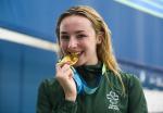 female Para swimmer Ellen Keane smiles and bites her gold medal