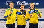 three male Ukrainian swimmers on the podium holding their medals