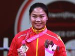 female powerlifter Yujiao Tan holds up her gold medal and a bunch of flowers