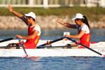 Male and female Chinese rowers on boat and wave at crowd