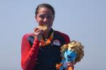 female Para triathlete Grace Norman bites her gold medal on the podium