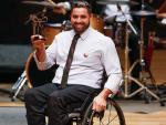 male wheelchair fencer Jovane Guissone holds up a trophy