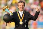 male Para equestrian rider Pepo Puch holds up his arms in celebration with a gold medal round his neck