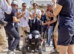 Woman in a wheelchair clapping hands and celebrating with a group of people standing