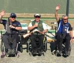 three male Para shooters in wheelchairs with Scottie Brydon in the middle waving to the crowd