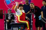 female powerlifter Xu Lili waves and smiles while sitting on the bench
