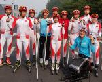 A woman in a sitting rollerski together with a group of ten rollerskiers 