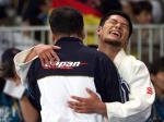 male judoka Satoshi Fujimoto hugs another man