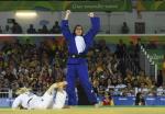 female judoka Naomi Soazo raises her arms straight up in the air in celebration