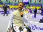 A man in a wheelchair wearing a fencing uniform