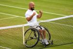 male wheelchair tennis player Stefan Olsson raises his fists in celebration at the net