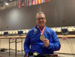 male Para shooter Richard Didier holds up his gold medal and smiles