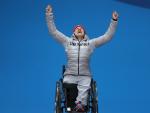 female Para alpine skier Anna-Lena Forster raises her arms in celebration on the podium