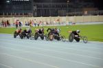 Group of men in racing chairs compete on a track