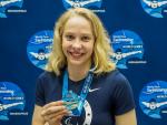 female Para swimmer Julia Gaffney smiles and holds up a gold medal