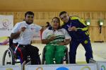 female Para shooter Maria Teresa Restrepo sitting a wheelchair with a male athlete either side holding up medals