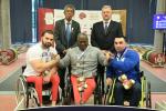 male Para powerlifter Mohammed Khamis Khalaf in the middle of two other powerlifters on the podium with their arms around eachother 
