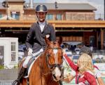 Latvian male dressage rider with celebral palsy smiles on a horse