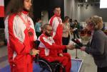 Man in wheelchair shakes hand with woman during medal ceremony