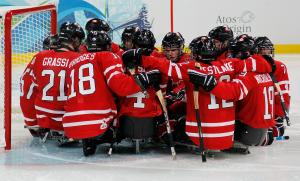 The Canadian Ice Sledge Hockey Team gathered around the goal.