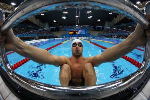 A picure of a man in the pool holding starting block with his hands