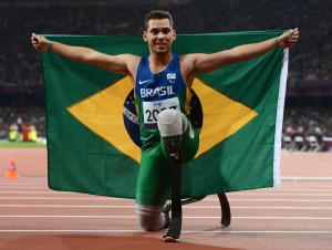 A picture of a man on the track posing with Brazilian flag in his hands