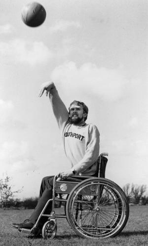 A picture of a man in a wheelchair shooting a basketball ball