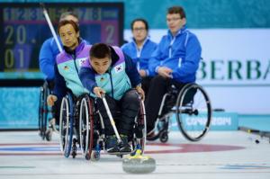 Woman throwing a stone in wheelchair curling.