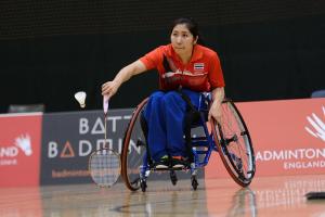Women in wheelchair playing badminton on the court.