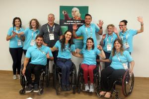 a group of para athletes raise their arms for a photo